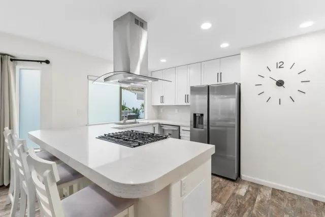 a kitchen with stainless steel appliances a refrigerator a stove a sink and white cabinets