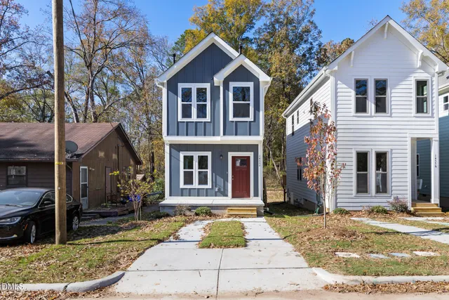 a view of a brick house with many windows plants and large tree