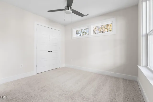 an empty room with windows and fan
