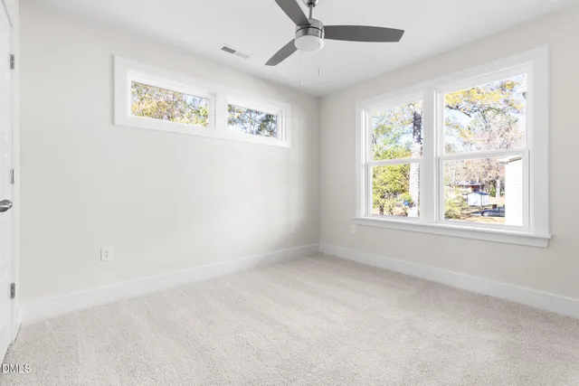 an empty room with windows and ceiling fan