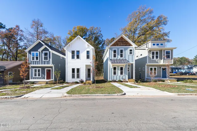 a view of residential houses with cars parked in front of it