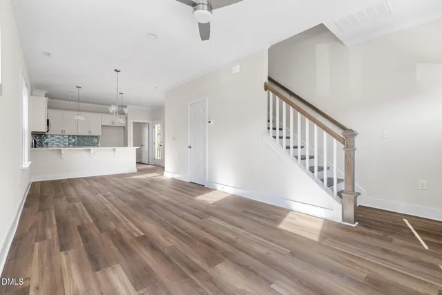 a view of a hallway with wooden floor and a kitchen view