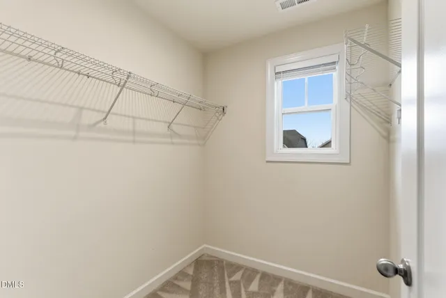 a spacious bedroom with a bed large window and a chandelier