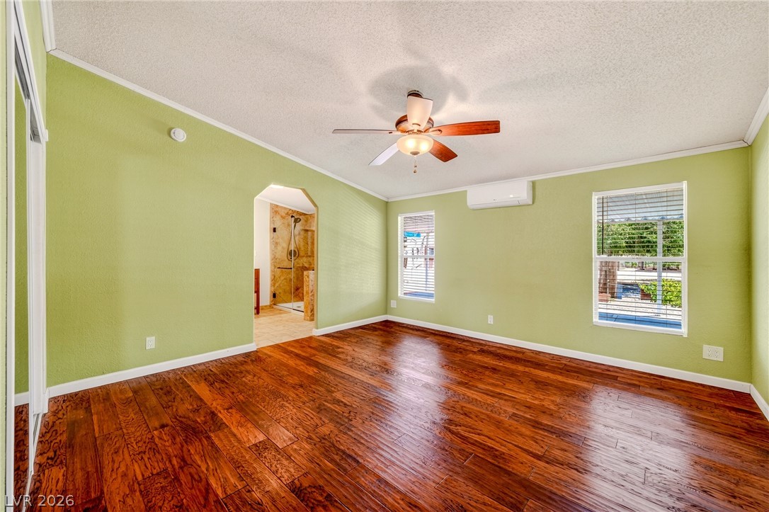 1831 West Horn Road Pahrump, NV 89048 - Photo 11 of 59 Rich hardwood floors complement light walls in this inviting primary bedroom, with a private bathroom entry.