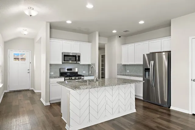 a kitchen with stainless steel appliances granite countertop a refrigerator stove microwave and sink