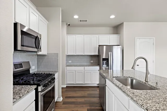 a kitchen with stainless steel appliances granite countertop a sink stove and refrigerator