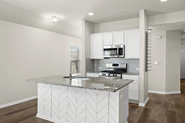 a kitchen with granite countertop a stove a sink and a refrigerator