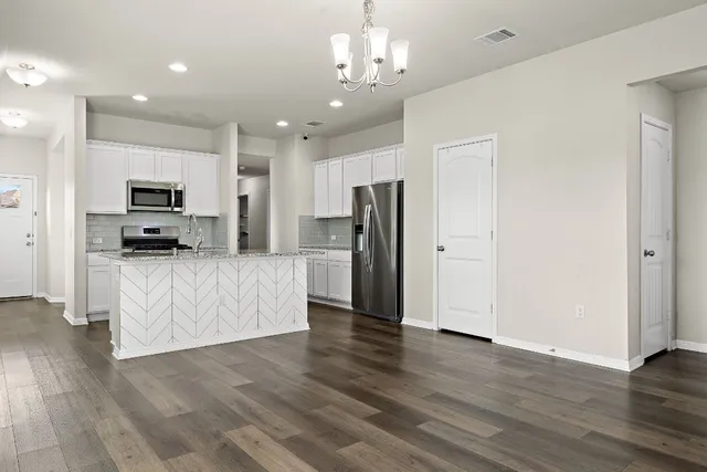 an empty room with wooden floor an empty space and a kitchen