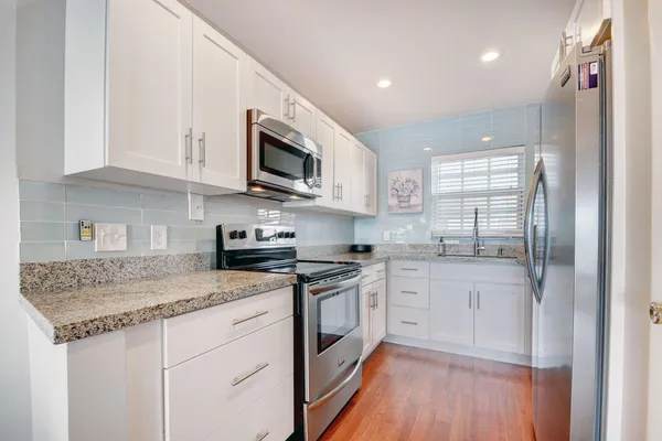 a kitchen with granite countertop a refrigerator and cabinets