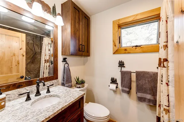 a bathroom with a granite countertop sink mirror vanity and toilet