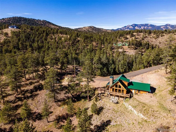 an aerial view of a house with a yard and mountain view in back