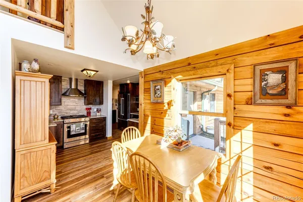 a view of a kitchen with kitchen island stainless steel appliances wooden floor dining table and chairs