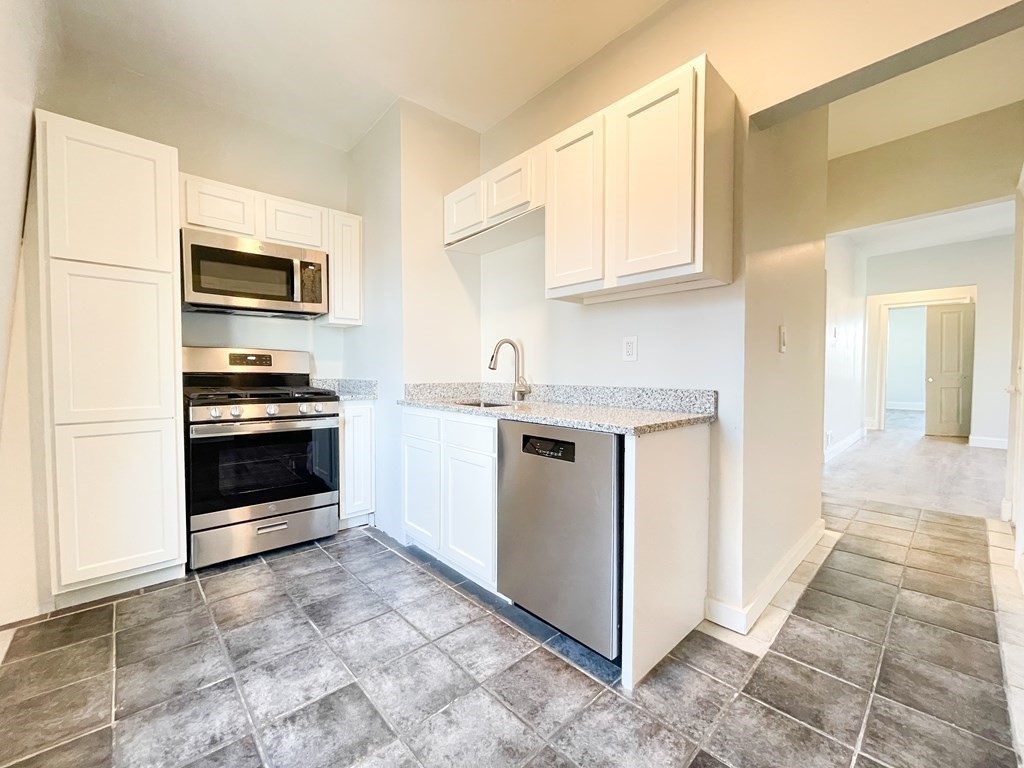 30 Woodbine Street Boston, MA 02119 - Photo 19 of 41 a kitchen with stainless steel appliances a stove a microwave and a sink
