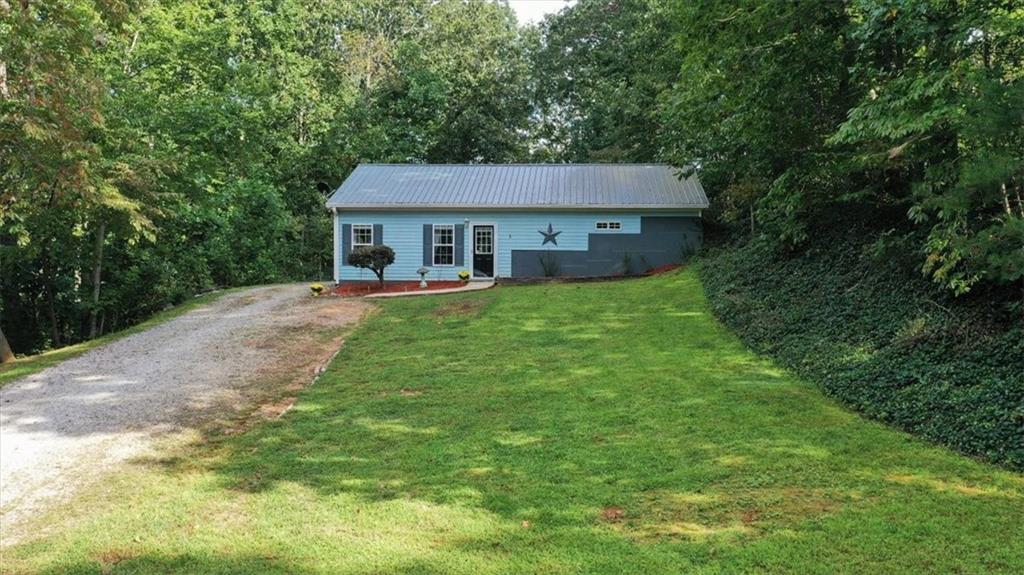a view of a house with a big yard potted plants and large tree