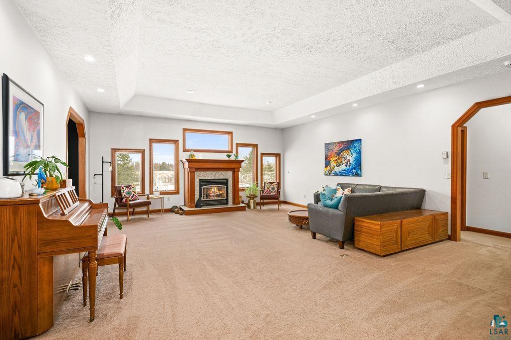 2542 Ziehl Road Carlton, MN 55718 - Photo 11 of 51 Living area with light carpet, a textured ceiling, arched walkways, a glass covered fireplace, and recessed lighting