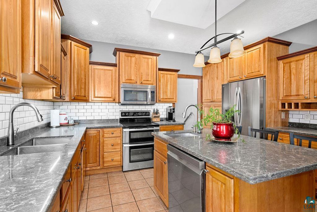 2542 Ziehl Road Carlton, MN 55718 - Photo 15 of 51 Kitchen with stainless steel appliances, light tile patterned floors, tasteful backsplash, and dark stone countertops