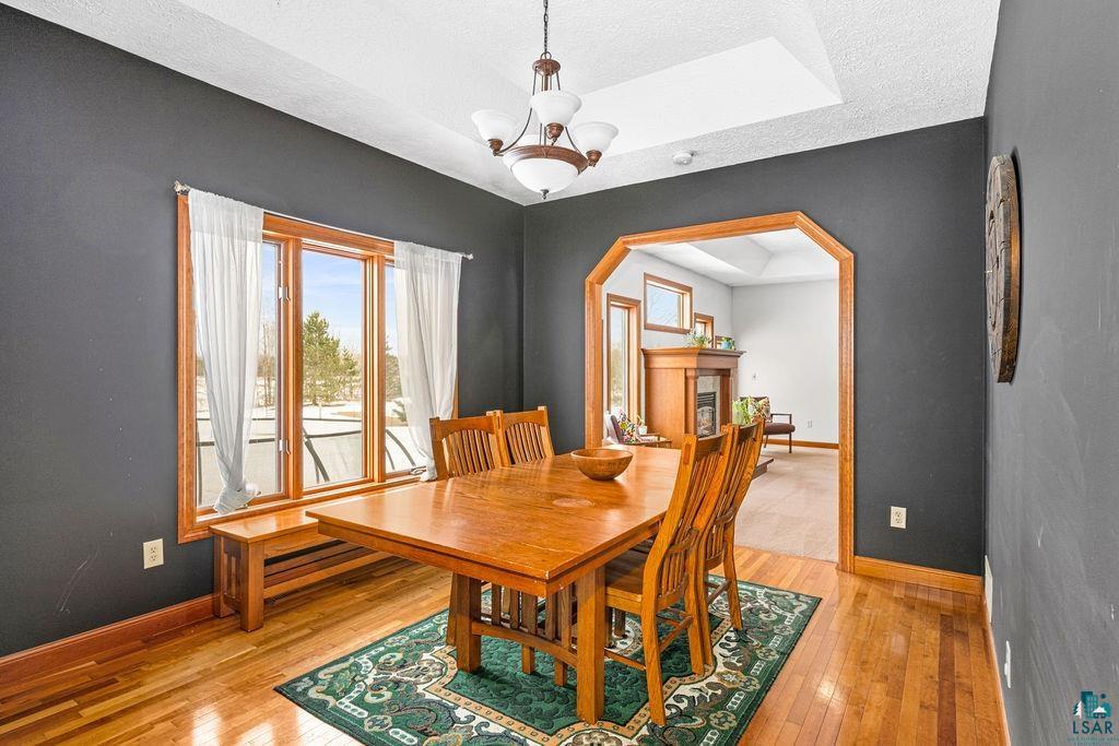 2542 Ziehl Road Carlton, MN 55718 - Photo 19 of 51 Dining room with hanging lights, arched walkways, light wood-style flooring, a raised ceiling, and a fireplace