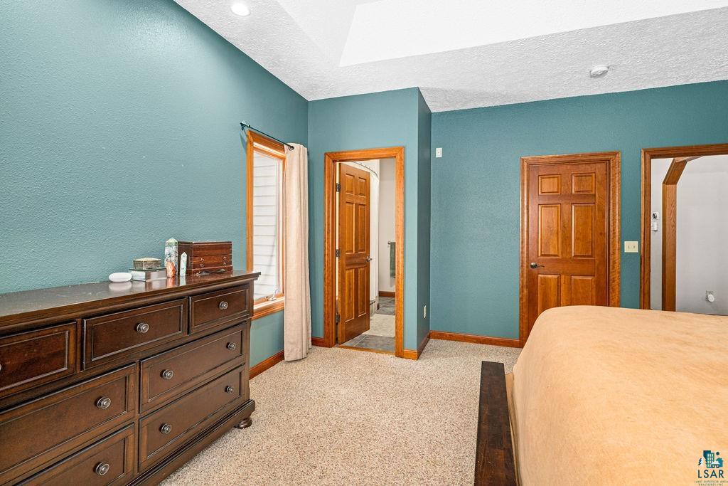 2542 Ziehl Road Carlton, MN 55718 - Photo 22 of 51 Bedroom with light colored carpet, a textured ceiling, arched walkways, and a textured wall