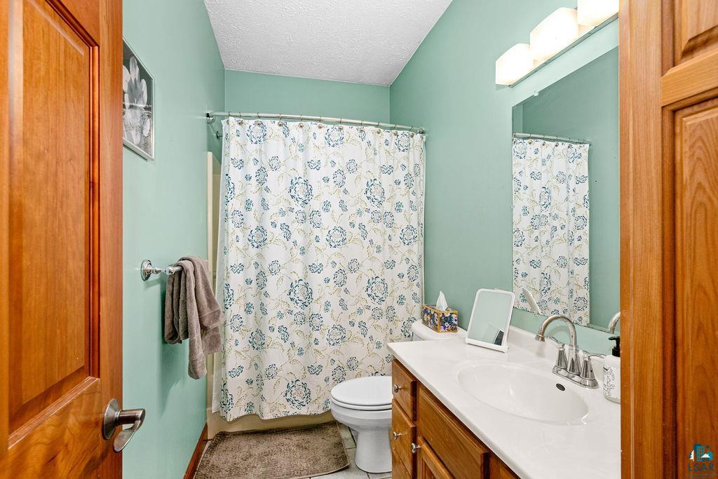 2542 Ziehl Road Carlton, MN 55718 - Photo 26 of 51 Bathroom featuring a textured ceiling, vanity, and shower / bath combination with curtain