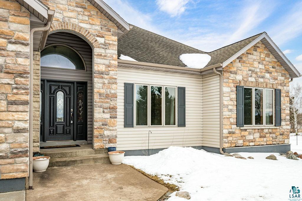 2542 Ziehl Road Carlton, MN 55718 - Photo 3 of 51 Snow covered property entrance featuring stone siding and roof with shingles
