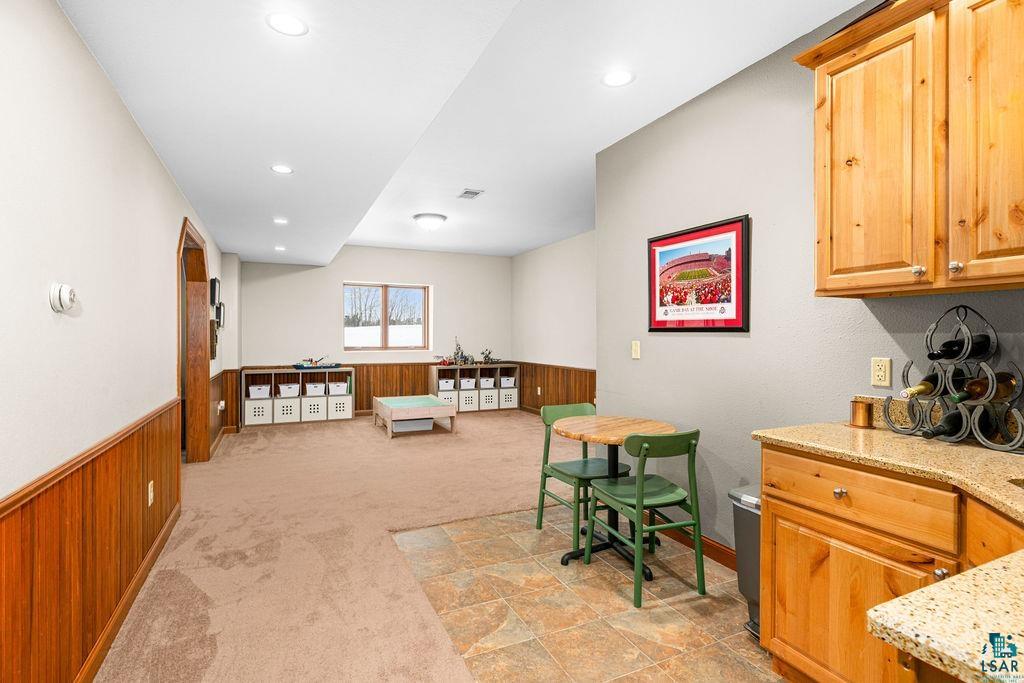 2542 Ziehl Road Carlton, MN 55718 - Photo 36 of 51 Bar area featuring light colored carpet, light stone counters, wooden walls, recessed lighting, and wainscoting