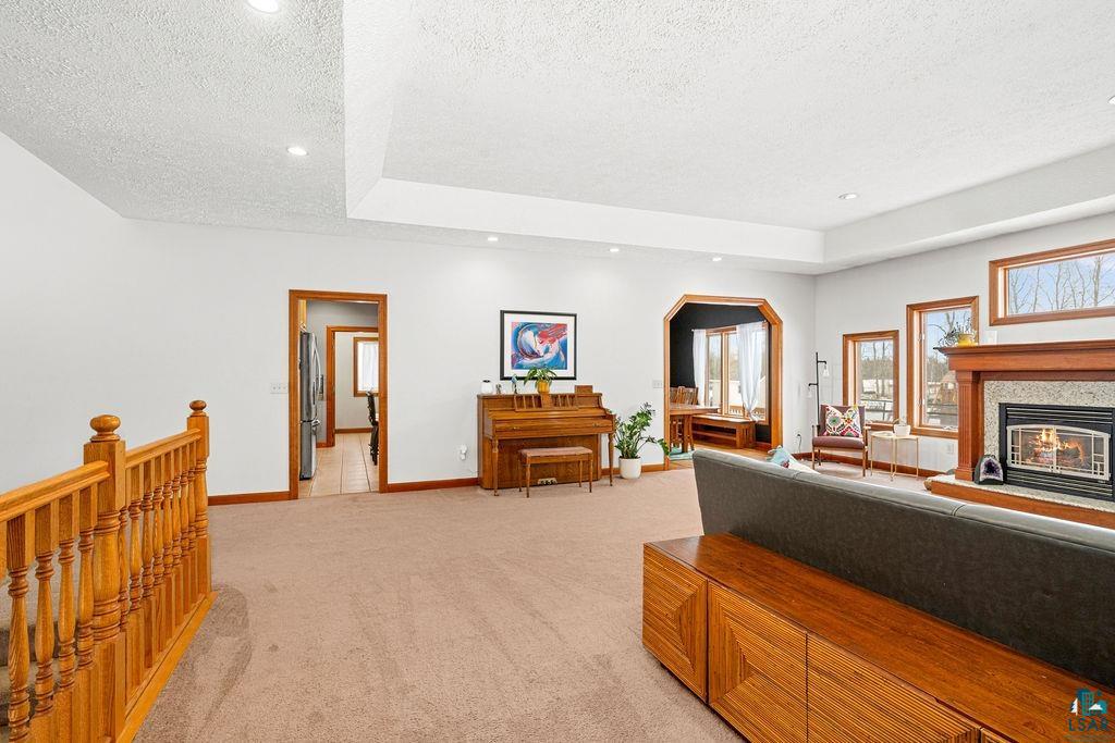 2542 Ziehl Road Carlton, MN 55718 - Photo 10 of 51 Living room featuring light colored carpet, a tray ceiling, a textured ceiling, a glass covered fireplace, and recessed lighting