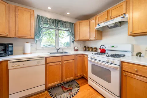 a kitchen with granite countertop white cabinets sink and white appliances