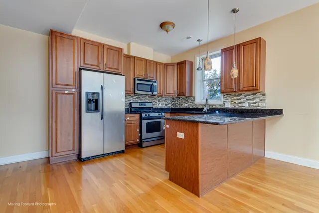 a kitchen with stainless steel appliances granite countertop a sink cabinets and wooden floor
