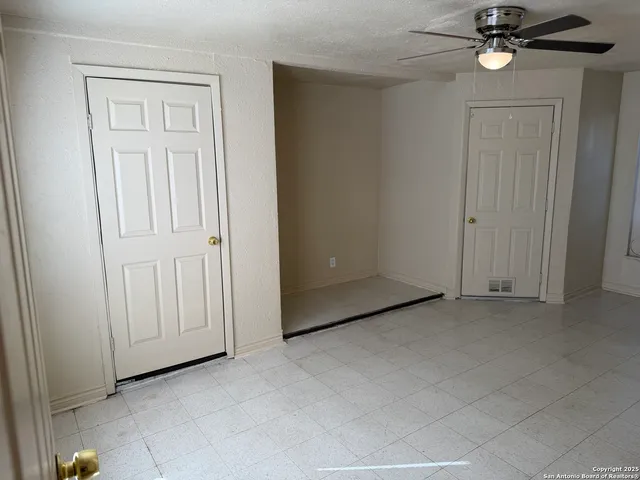 an empty room with windows and fan