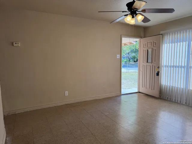 an empty room with wooden floor fan and windows