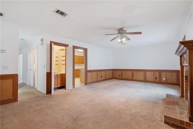 an empty room with chandelier fan and windows
