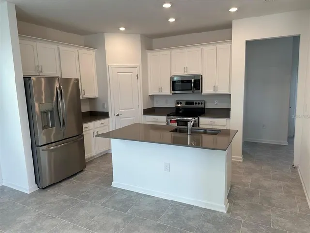 a kitchen with granite countertop a refrigerator and a stove top oven