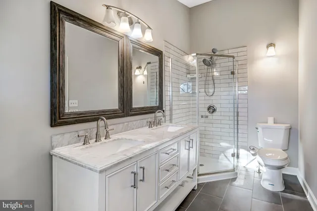 a bathroom with a double vanity sink toilet and shower