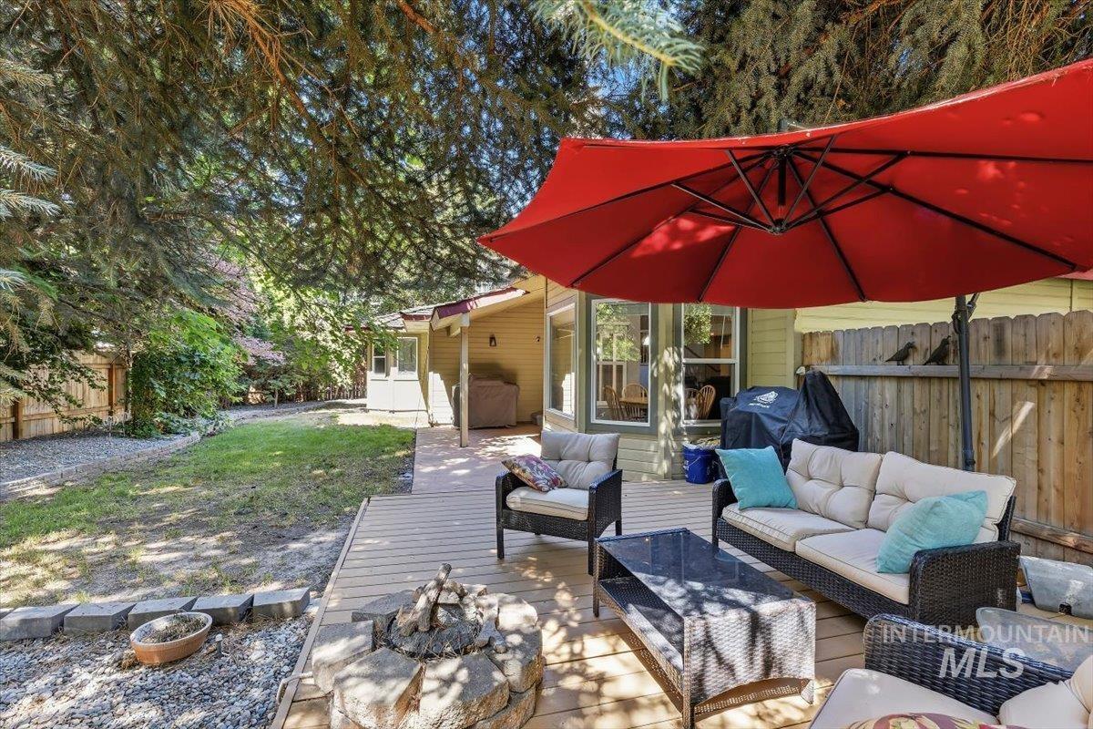 8001 West Innsbrook Court Boise, ID 83704 - Photo 35 of 39 Expansive backyard featuring a wood deck, stone fire pit, gravel landscaping, and mature trees providing natural shade