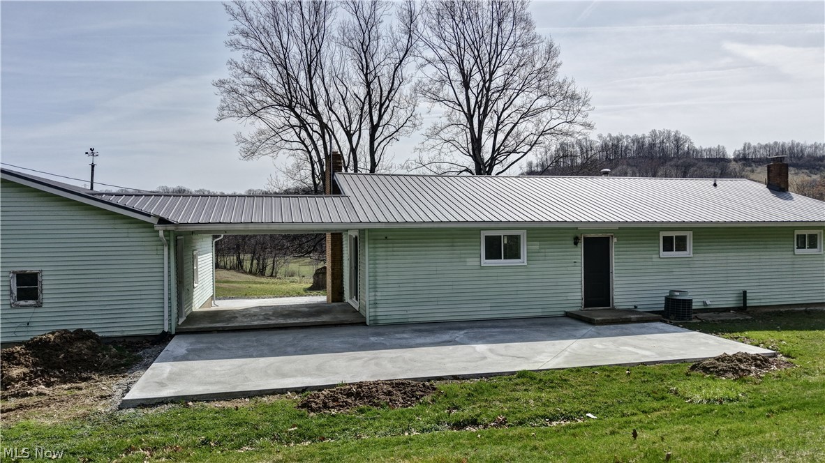 3265 York View Road Southwest New Philadelphia, OH 44663 - Photo 31 of 45 Rear view of house with a chimney, a metal roof, a patio, and a yard