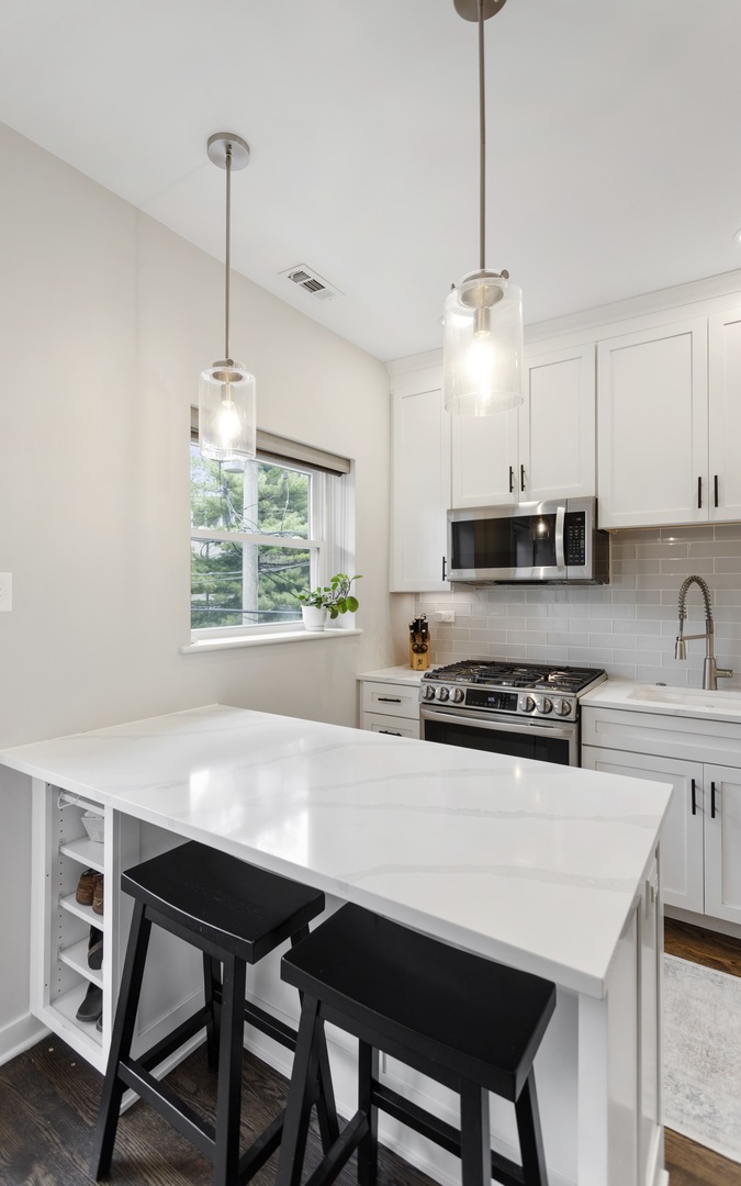 1214 West Webster Avenue, Unit 2E Chicago, IL 60614 - Photo 13 of 23 a kitchen with stainless steel appliances a table chairs and a wooden floor