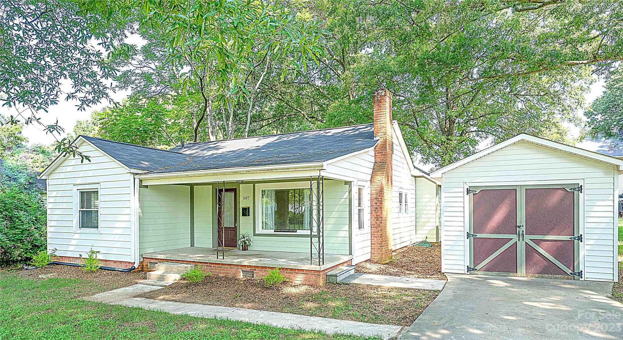 a view of a house with a yard and large tree