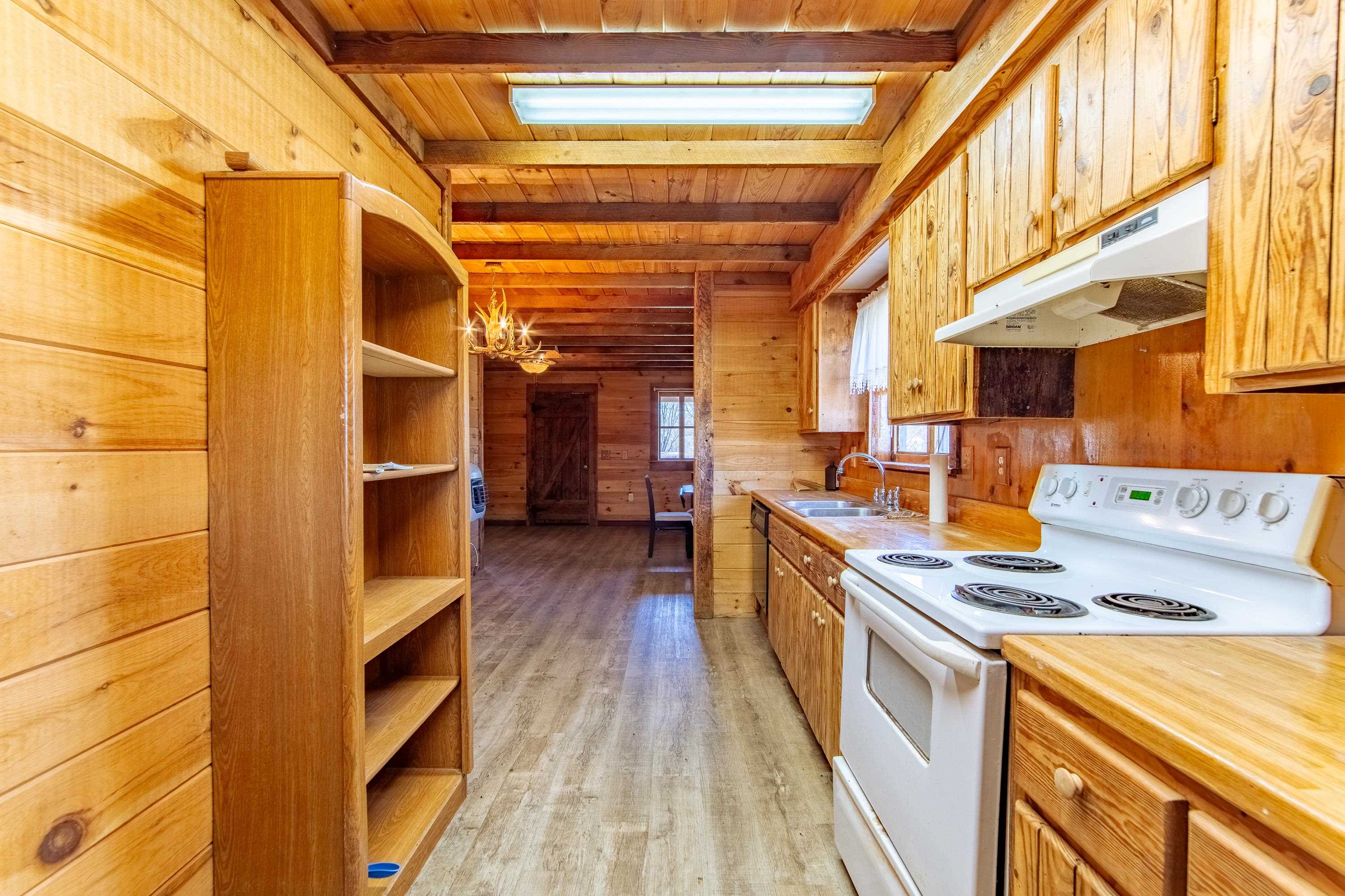 355 Bellis Road Savannah, TN 38372 - Photo 10 of 26 Kitchen featuring wooden walls, under cabinet range hood, a sink, dishwasher, range with electric stovetop, and beamed ceiling
