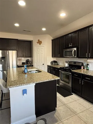 a kitchen with stainless steel appliances granite countertop a stove a sink dishwasher a refrigerator and a microwave