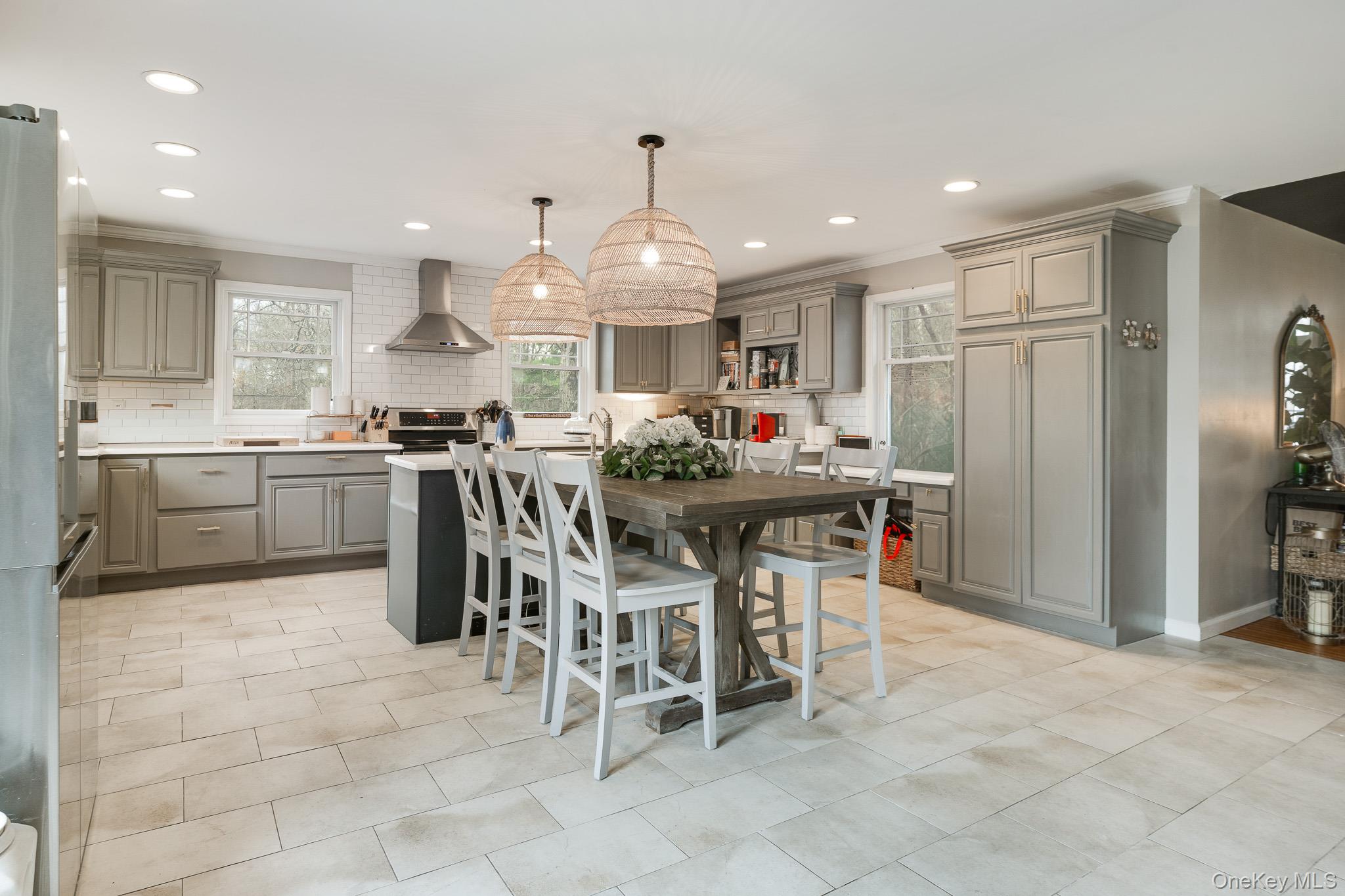 112 Pleasantview Road Pleasant Valley, NY 12569 - Photo 10 of 30 Kitchen featuring gray cabinets, a kitchen island with sink, hanging light fixtures, wall chimney exhaust hood, and appliances with stainless steel finishes