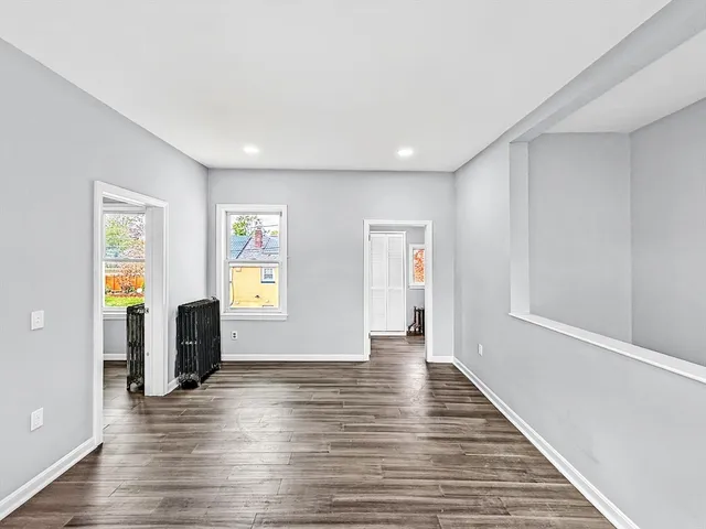 a view of an empty room with window and wooden floor