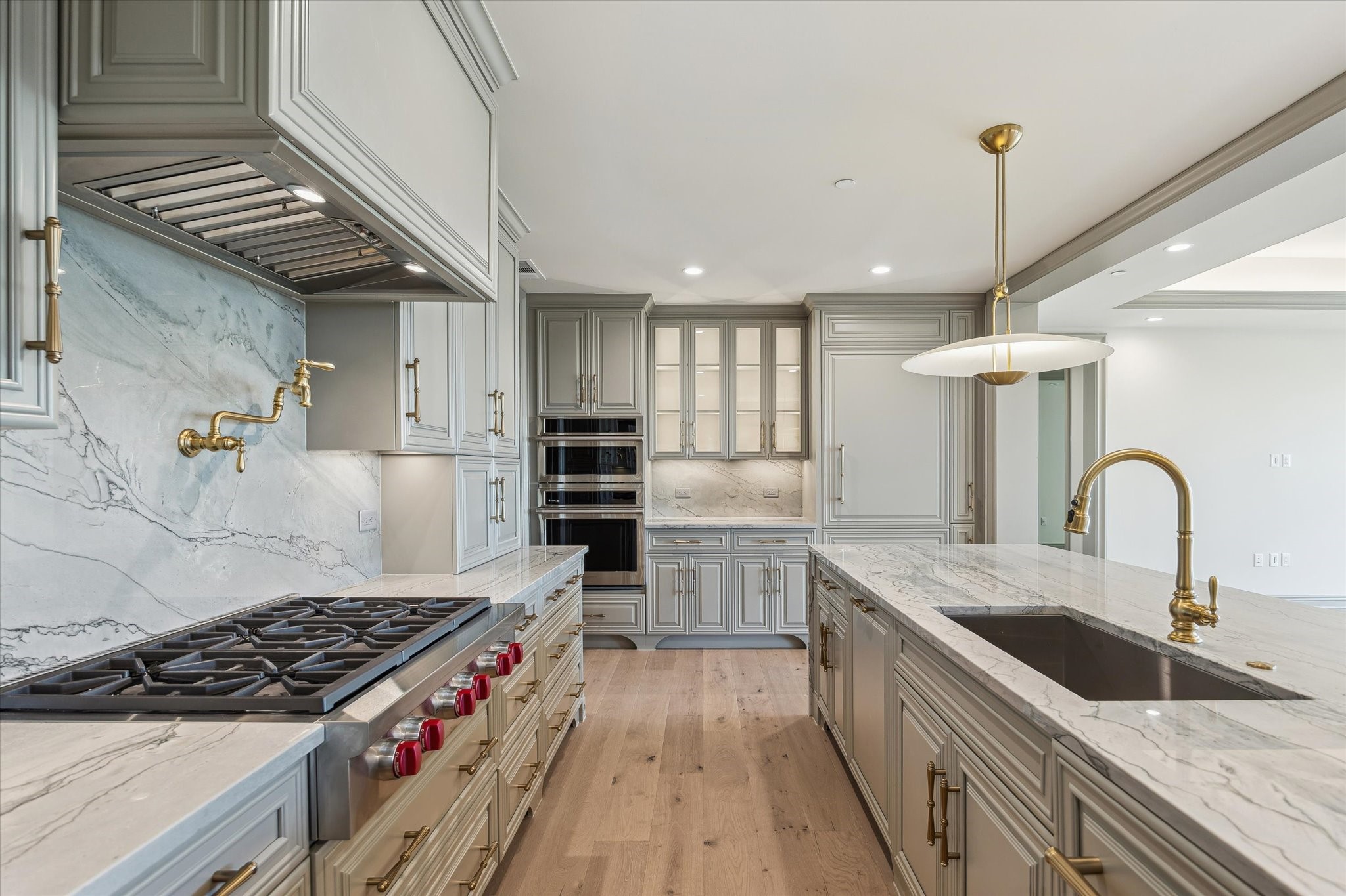 1717 Bissonnet Street, Unit 1105 Houston, TX 77005 - Photo 5 of 32 Wolf gas six burner cooktop, pot filler, slab Quartzite backsplash, glass front cabinetry, Kohler Artifacts brass plumbing fixtures and Advantium microwave/oven combination.