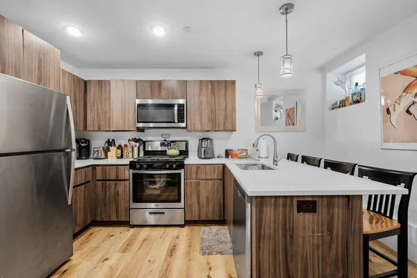 a kitchen with stainless steel appliances granite countertop a refrigerator a stove a sink dishwasher and a refrigerator with wooden floor