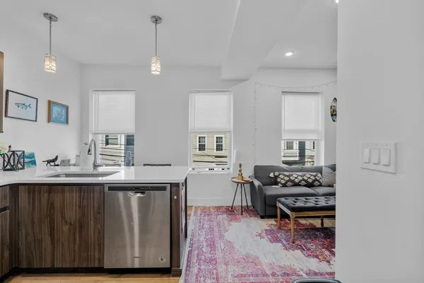 a kitchen with stainless steel appliances a stove a sink dishwasher and a dining table with wooden floor