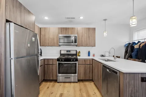 a kitchen with a sink a refrigerator and a stove top oven with wooden floor