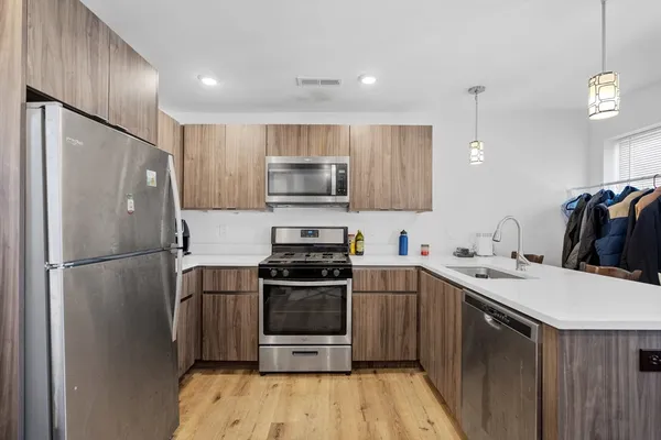 a kitchen with a sink a refrigerator and a stove top oven with wooden floor