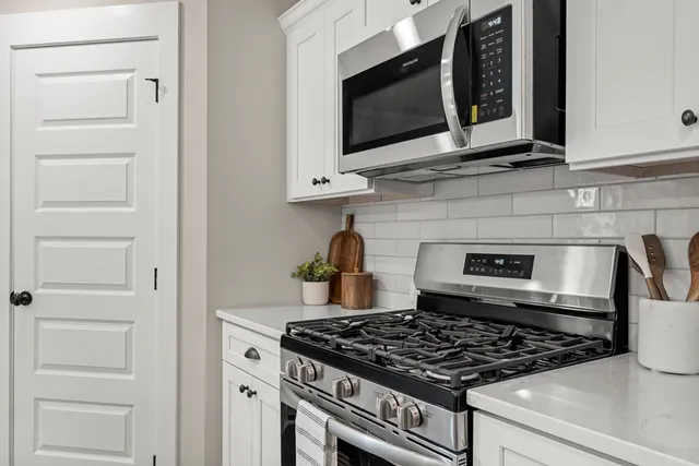 a stove top oven sitting inside of a kitchen and white cabinets