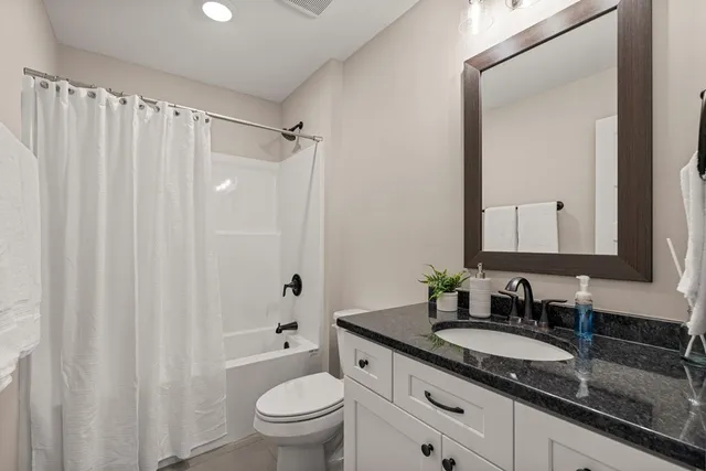 a bathroom with a granite countertop sink toilet and shower