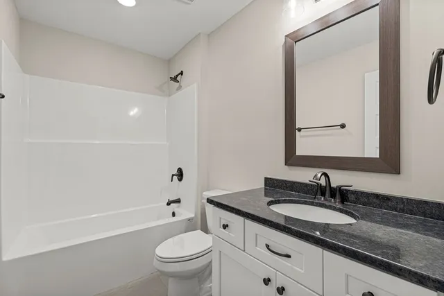 a bathroom with a granite countertop sink a toilet and a large mirror