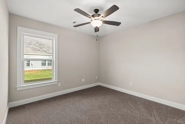 an empty room with a window and a fan